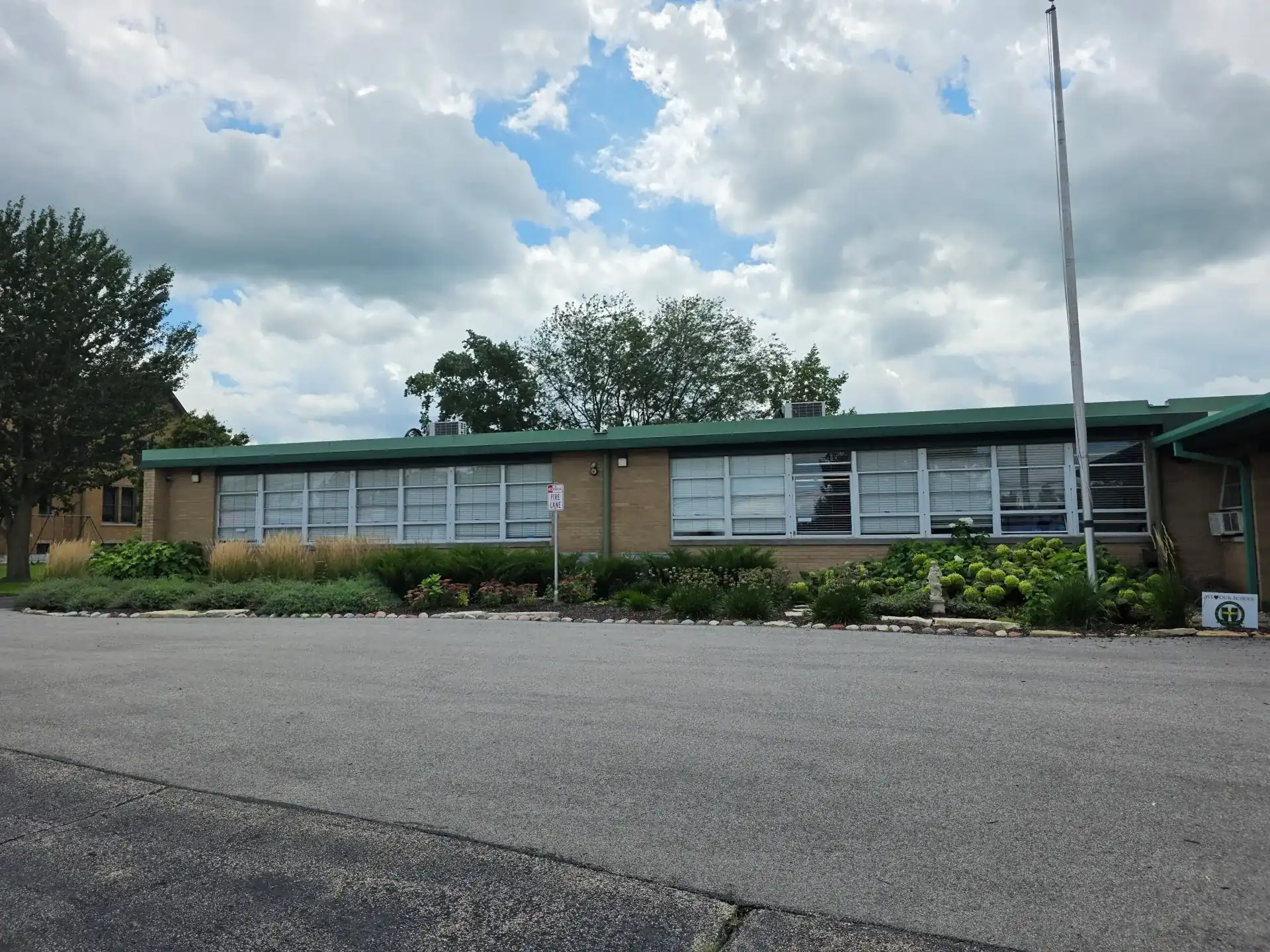 Low-rise commercial building with a long row of exterior windows beneath a cloudy sky.