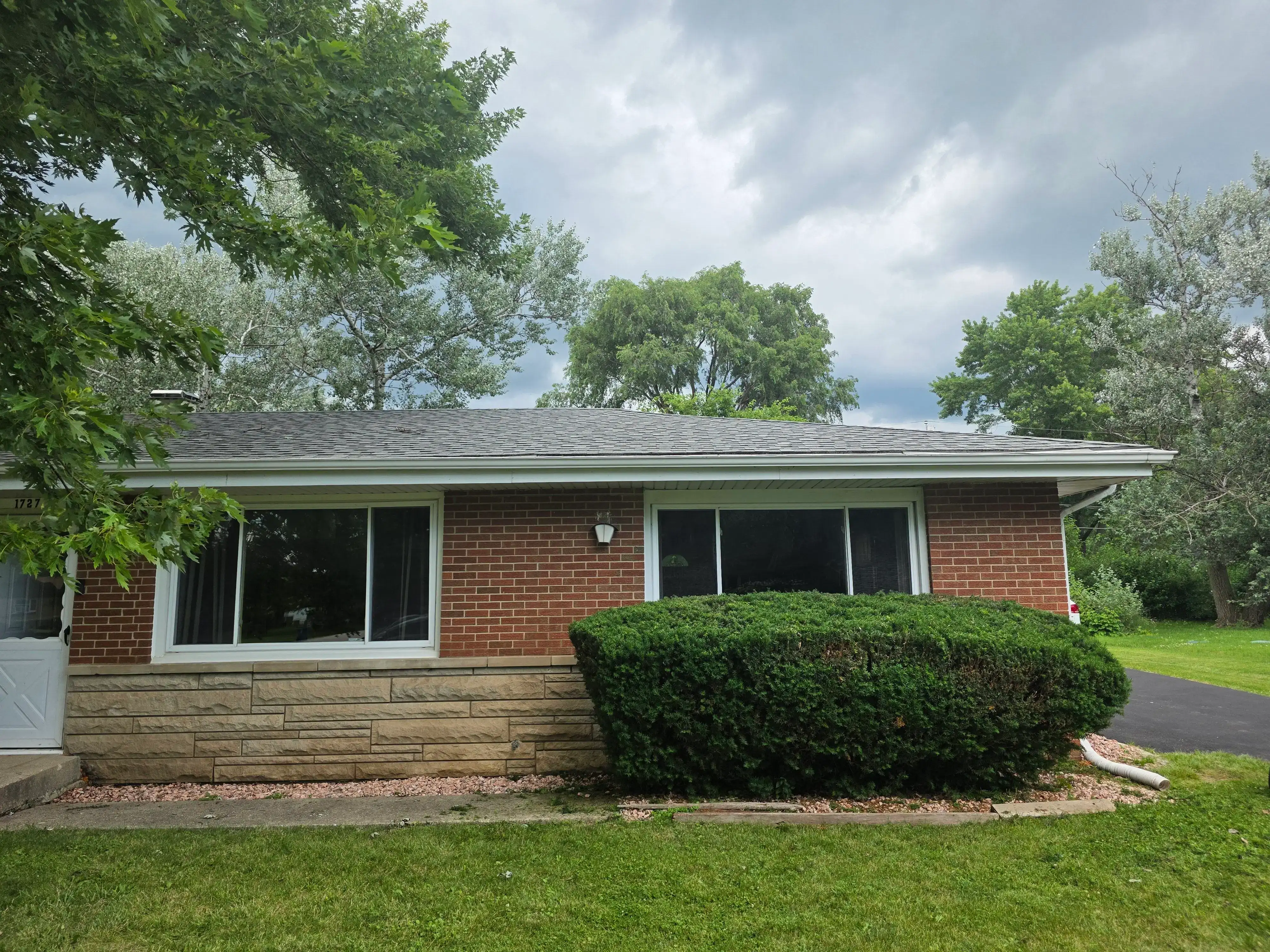 Residential brick home with clean front windows and a neatly trimmed hedge along the facade.