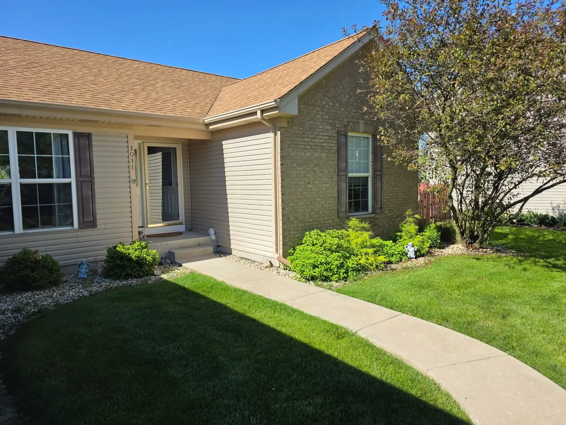 Bright residential home exterior with clean front windows, entry door, roofline, and landscaped yard.